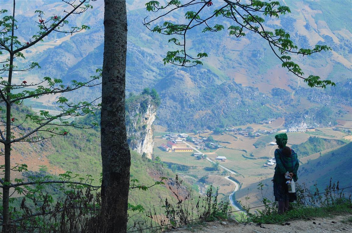 A woman in traditional dress looking out over a valley from a mountain road