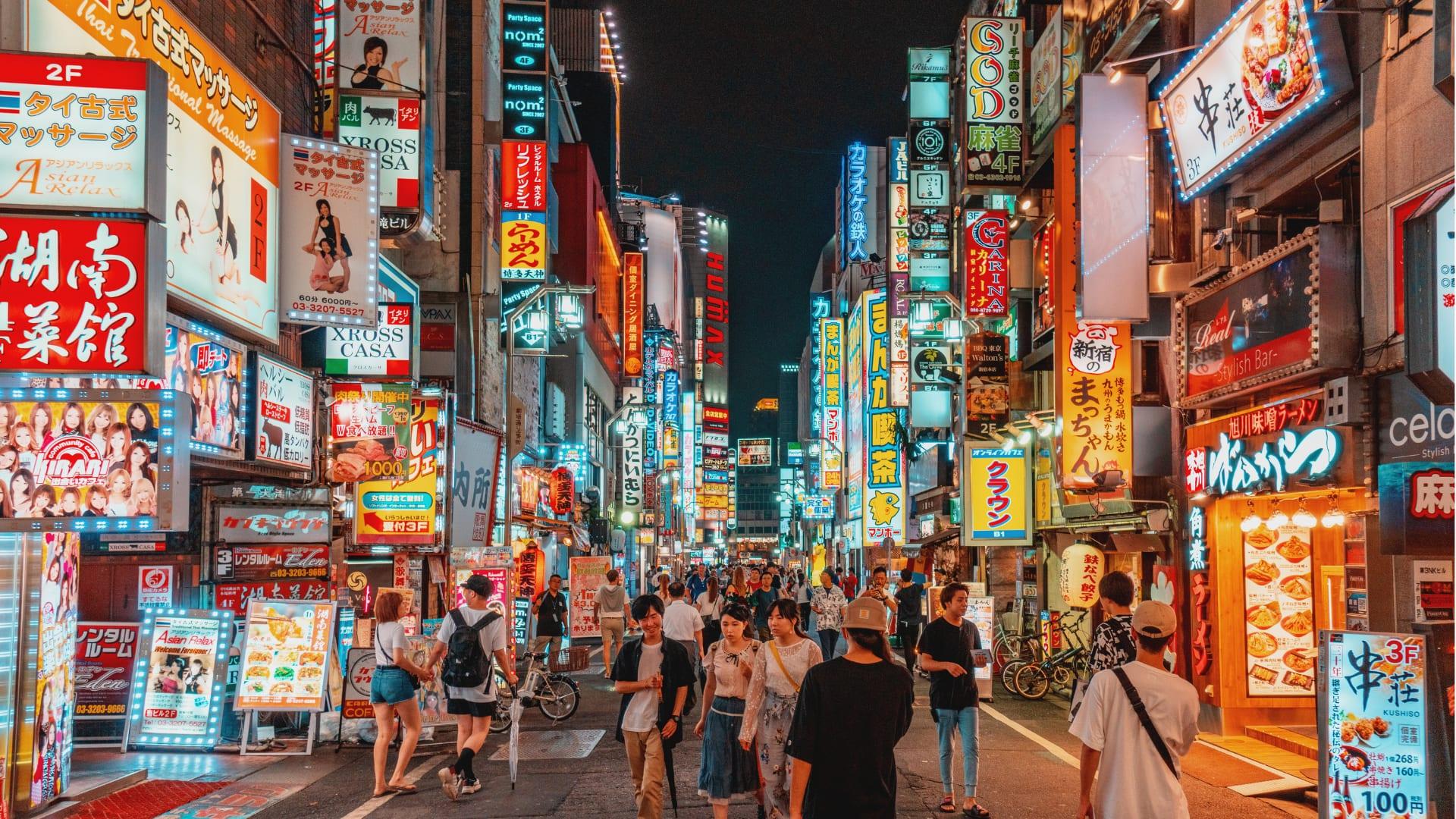 Una via di Tokyo di sera, tra le insegne al neon