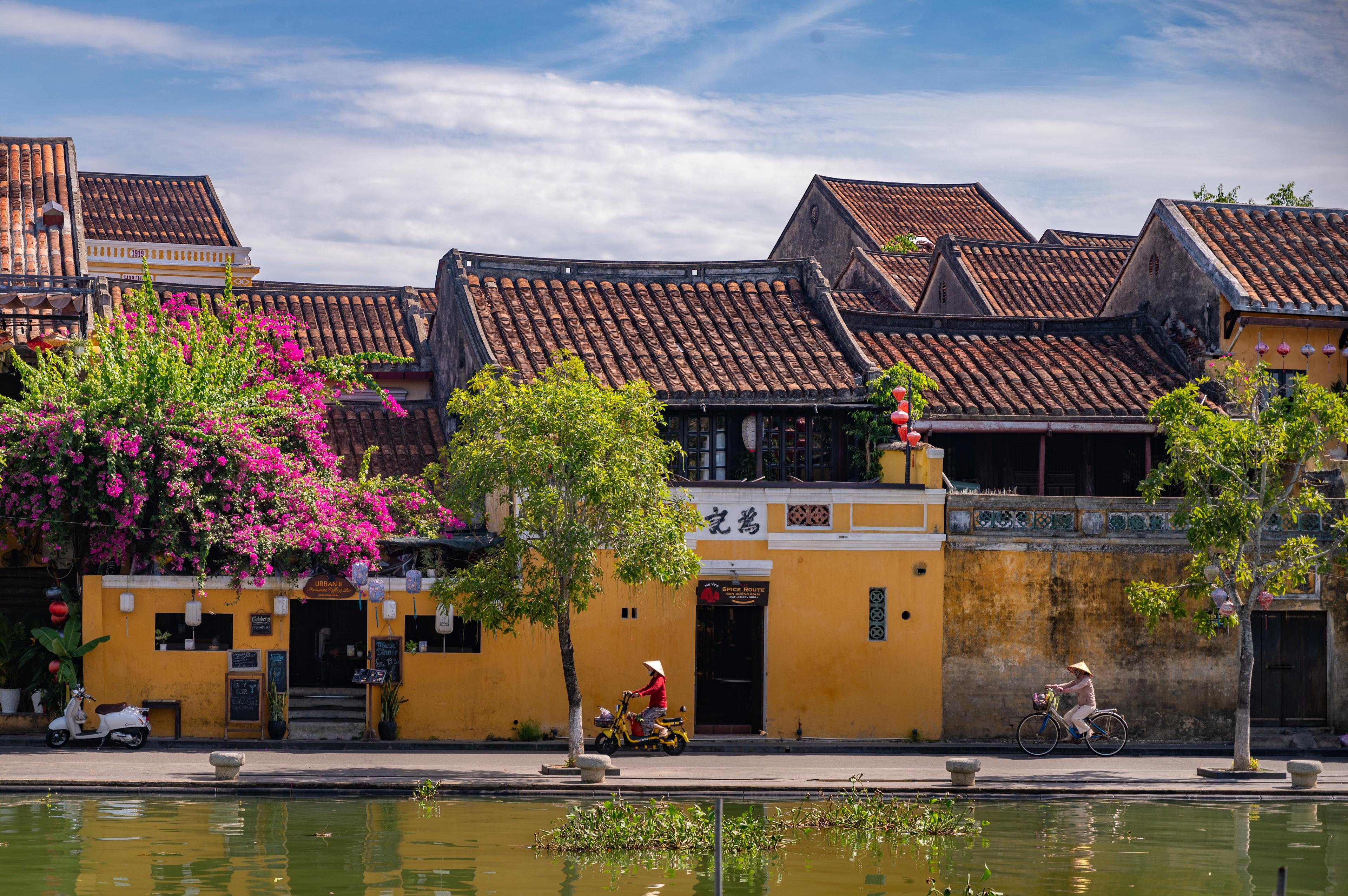 Case-bottega gialle con tetti di tegole lungo il fiume nella città antica di Hoi An